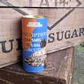 A cylindrical tin of Bristol Dockyards Scrumptious Caramel & Sea Salt Biscuits sits on a rustic wooden crate.