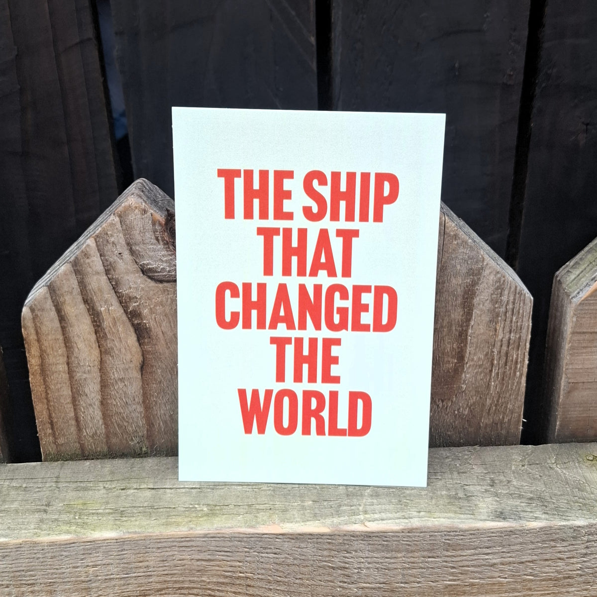 Postcard with 'The Ship That Changed The World' in orange lettering.