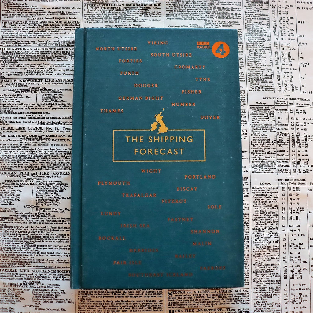 A hardcover book titled 'The Shipping Forecast' lying on a surface with text, featuring a blue cover with gold text and a map outline.