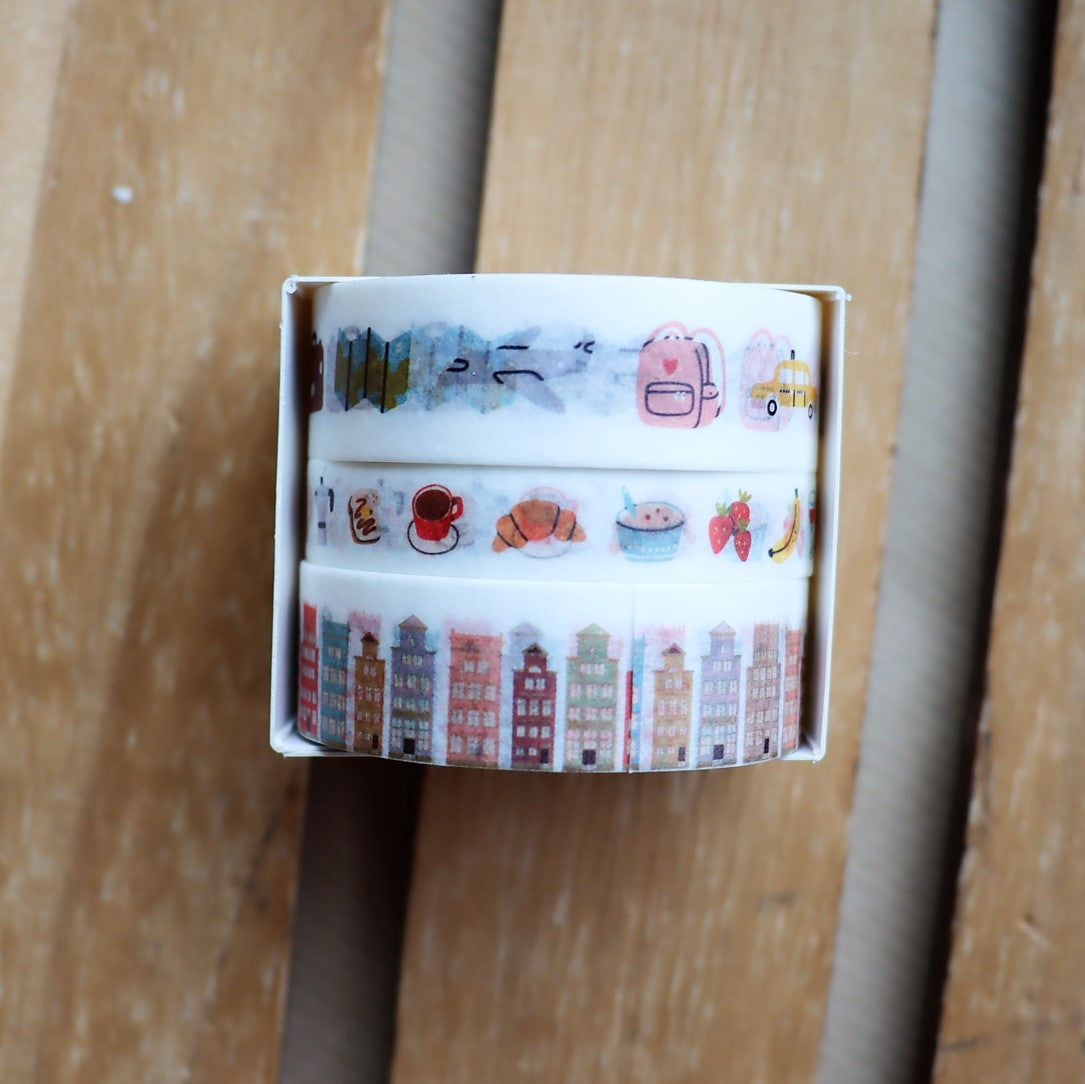 Three rolls of washi tape with different designs, placed side by side on a wooden surface.