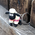 Keychain with Shaun the Sheep wearing a colourful sweater on a wooden surface